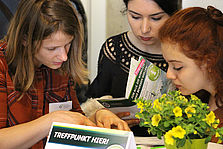 Eine junge Frau erklärt zwei Mädchen etwas anhand einer Broschüre. © Hochschule Geisenheim
