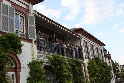 Menschengruppe steht auf dem Balkon der Villa
