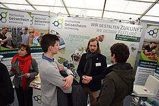 Eine Gruppe von Menschen steht auf einem Messestand und unterhält sich. © Hochschule Geisenheim