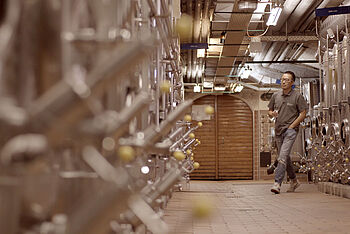 Ein junger Chinese läuft durch einen Weinkeller mit Stahltanks. © Hochschule Geisenheim