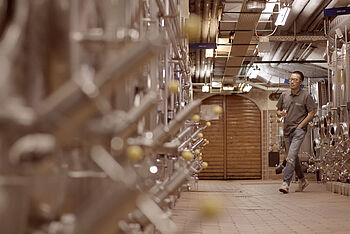 Ein junger Chinese läuft durch einen Weinkeller mit Stahltanks. © Hochschule Geisenheim