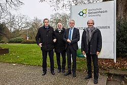 Gruppenbild, im Hintergrund das Schild der Hochschule