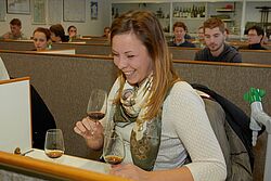 Studentin lachend mit Weinglas in ihrer Hand