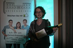 Student mit grosser Weinflasche in den Haenden