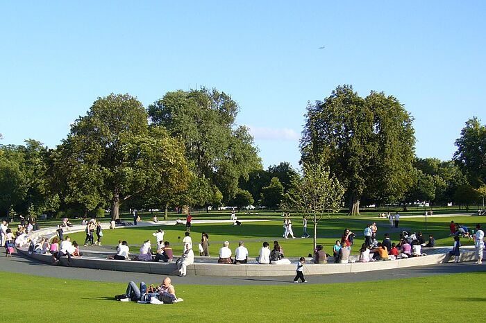 Menschen sitzen auf und neben einem Steinelement in einem grünen Park. © Hochschule Geisenheim