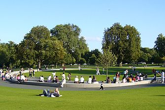 Menschen sitzen auf und neben einem Steinelement in einem grünen Park. © Hochschule Geisenheim