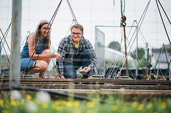Ein Student und seine Dozentin sitzen vor einer technischen Installation und führen Messungen durch © Hessen schafft Wissen – Steffen Böttcher 