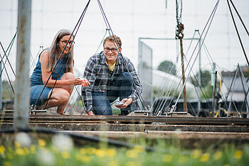 Ein Student und seine Dozentin sitzen vor einer technischen Installation und führen Messungen durch © Hessen schafft Wissen – Steffen Böttcher 