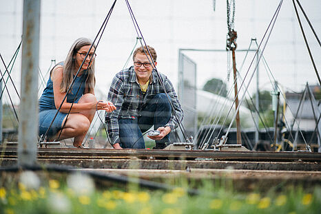 Ein Student und seine Dozentin sitzen vor einer technischen Installation und führen Messungen durch © Hessen schafft Wissen – Steffen Böttcher 