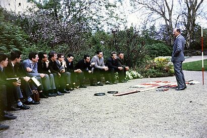 Gruppe sitzend und Mann steht vor ihnen