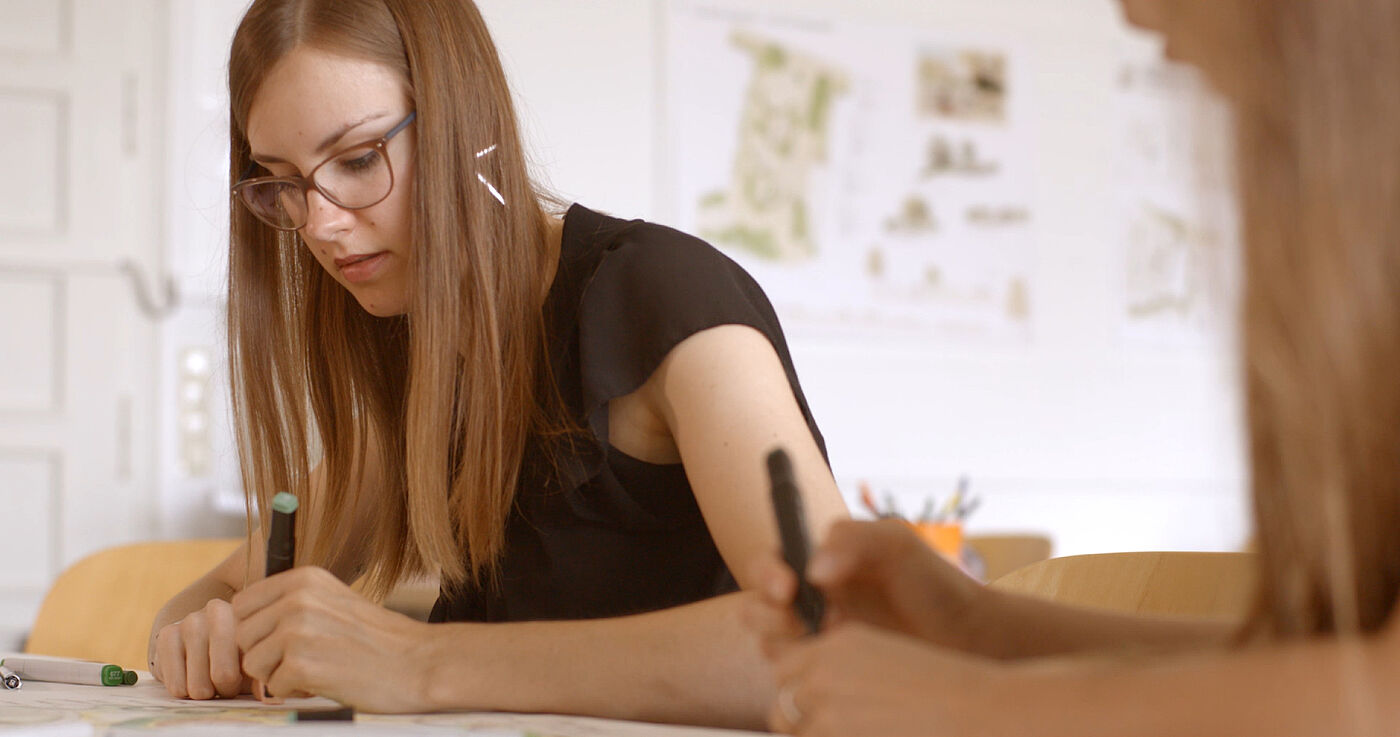 Zwei junge Frauen kolorieren einen Plan; im Hintergrund hängen weitere Pläne. © Hochschschule Geisenheim