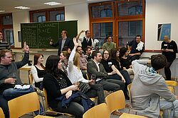 Teilnehmer sitzen auf Holzstühlen