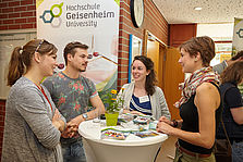 Vier junge Menschen stehen an einem Tisch und unterhalten sich angeregt. © Hochschule Geisenheim / Winfried Schönbach