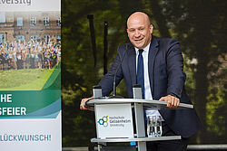 Mann hält lächelnd Rede auf der Bühne 