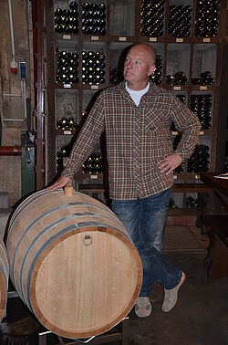 Mann lehnt sich an Weinfass