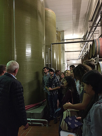 Exkursionsgruppe neben Tanks