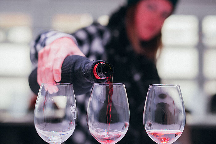 Eine junge Frau gießt Rotweine zum Verkosten in drei Gläser. © Hochschule Geisenheim / Steffen Boettcher