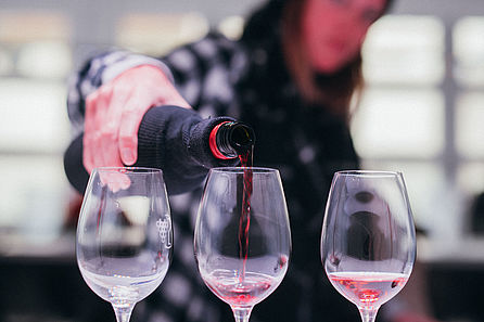 Eine junge Frau gießt Rotweine zum Verkosten in drei Gläser. © Hochschule Geisenheim / Steffen Boettcher