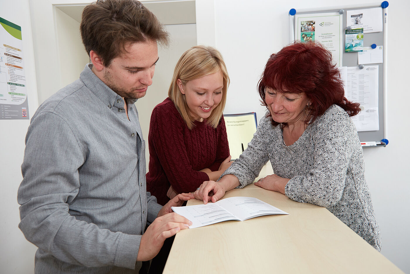 Eine Mitarbeiterin erklärt zwei Studierenden anhand einer Broschüre etwas. © Hochschule Geisenheim / Winfried Schönbach