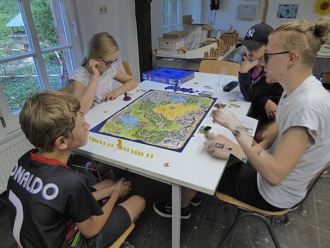 [Translate to English:] Kinder und Betreuer spielen ein Brettspiel