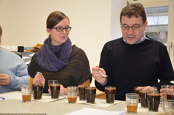 Mann und Frau sitzen vor mit Kaffee gefüllten Gläsern 