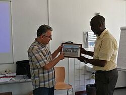 Teilnehmer übergibt Kursleiter gerahmtes Bild als Dankeschön 