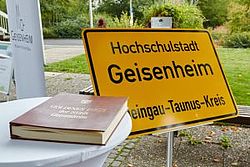 Schild Hochschulstadt Geisenheim im Hintergrund von liegenden Buch