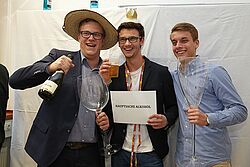 Drei Studenten halten verschiedenen Dinge in ihren Händen und lachen
