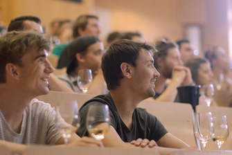 Studierende sitzen in einer Vorlesung und schauen gebannt nach vorne. Vor ihnen stehen Weingläser. © Hochschschule Geisenheim