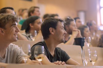 Studierende sitzen in einer Vorlesung und schauen gebannt nach vorne. Vor ihnen stehen Weingläser. © Hochschschule Geisenheim
