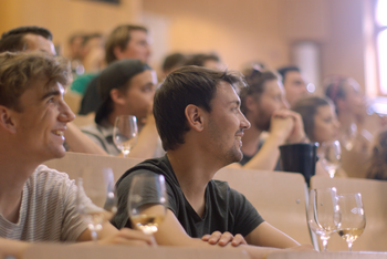 Studierende sitzen in einer Vorlesung und schauen gebannt nach vorne. Vor ihnen stehen Weingläser. © Hochschschule Geisenheim