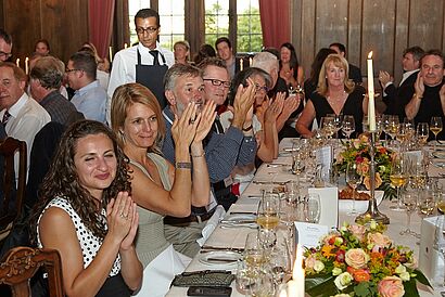 Gäste sitzen klatschend am Tisch