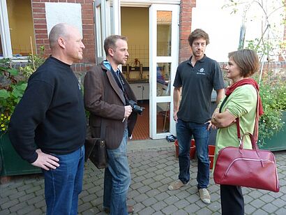 Drei Männer und eine Frau stehen draussen 