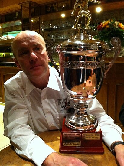 Weinelf-Kapitaen mit Pokal