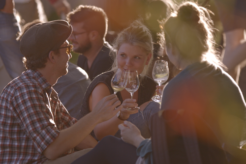 Eine Gruppe junger Menschen sitzt zusammen und stößt mit Wein an. © Hochschschule Geisenheim