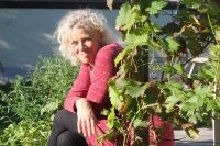 Frau Kreyenschmidt sitzt auf Holztreppe und ist von Pflanzen umgeben