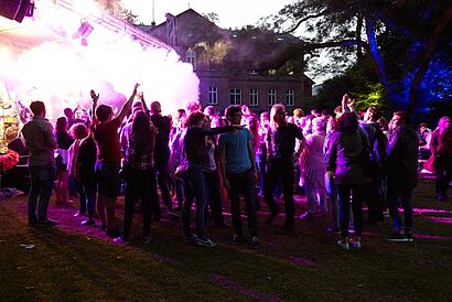 Studenten im Dunkeln umgeben von farbiger Rauchwolke
