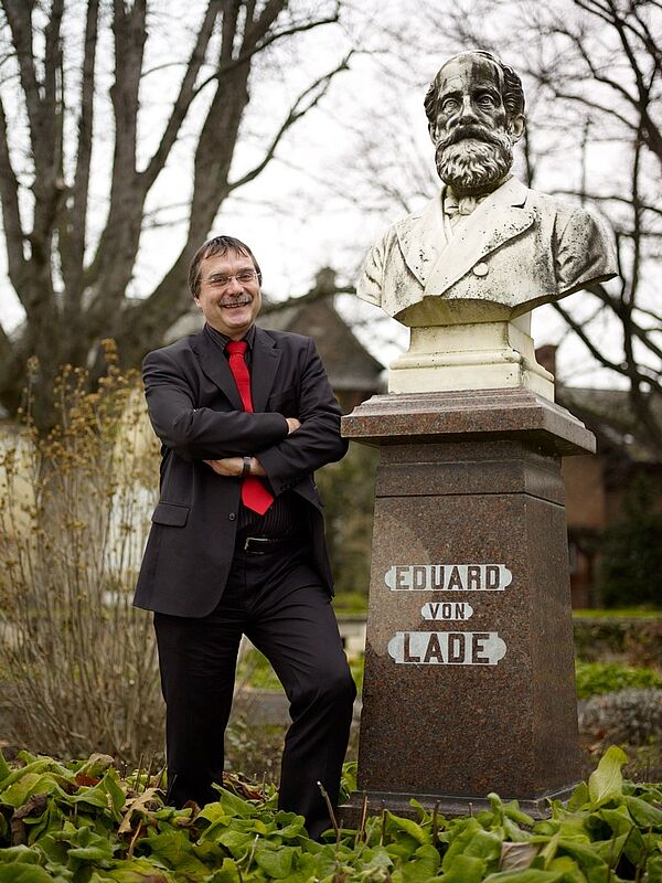 Professor neben Denkmal
