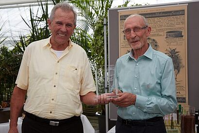 Zwei Männer halten Preis in den Händen 