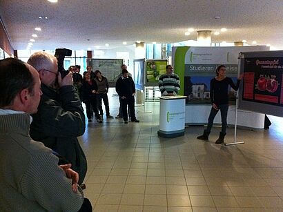 Zuschauer und Studentin vor dem Poster
