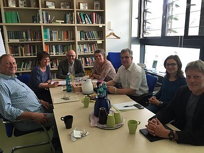 Gruppe sitzt am Tisch und alle schauen in die Kamera