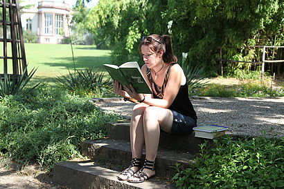 Studentin liest und sitzt dabei auf einer Stufe