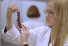 Eine junge Frau im weißen Laborkittel zupft einzelne Johnnisbeeren von einer Rispe. © Hochschschule Geisenheim