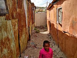 Eine Gasse in einer informellen Siedlung. Die "sheds" sind ohne Erlaubnis und Fundament auf Sand gebaut. Eine Gasse in einer informellen Siedlung. Die "sheds" sind ohne Erlaubnis und Fundament auf Sand gebaut.