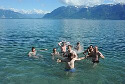 Teil der Mannschaft badet im Wasser mit den Bergen im Hintegrund