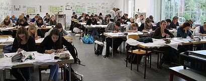 Studenten sitzen an Tischen und zeichnen