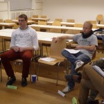 Zwei Männer sitzen auf Holzstühlen